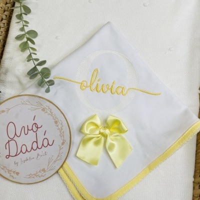 Fralda branca com bordado amarelo com o nome Olívia e laço amarelo