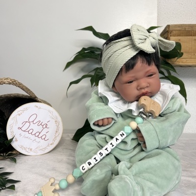 Boneco bebé com roupa verde e prendedor de chupeta personalizado.