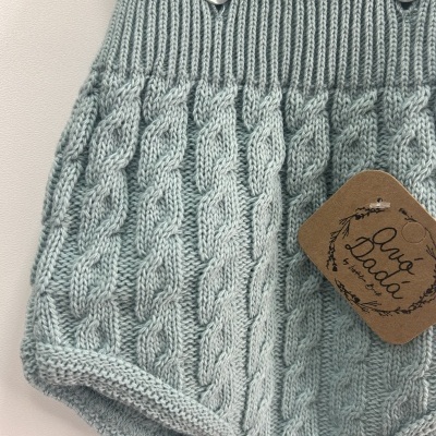 Cueiro de malha cinzento claro com padrão de tranças e botões prateados