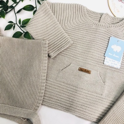 Conjunto de roupa infantil bege em malha com bolso e calças.