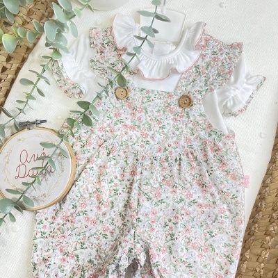 Conjunto de roupa de bebé branco e floral com botões de madeira.