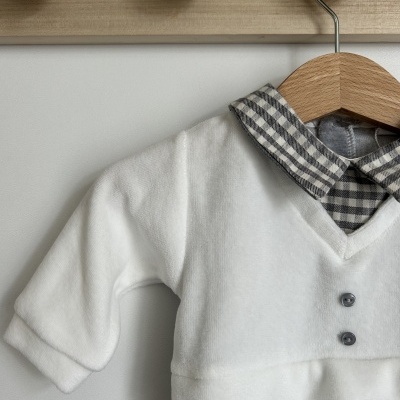 Roupa de bebé com camisa xadrez cinza e branca e camada branca com botões pendurada
