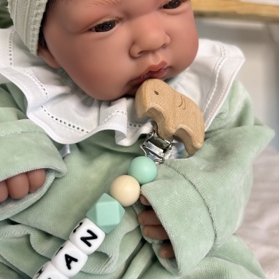 Boneca realista com roupa verde claro e prende-chupeta com contas e clipe de madeira em forma de elefante