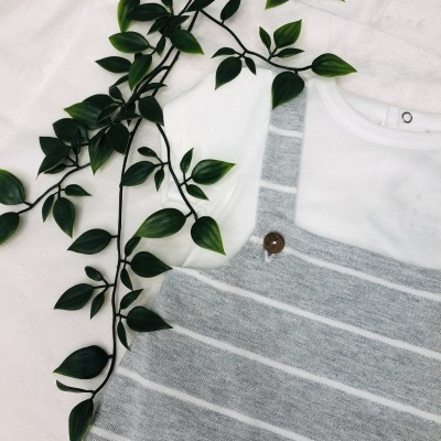 Conjunto de roupa infantil branco e cinzento com planta verde