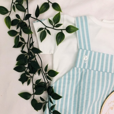 Conjunto de roupa para bebé branco e azul claro com folha verde ao lado