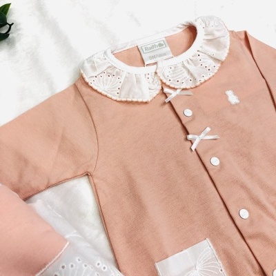 Roupa de bebé rosa com gola branca bordada e botões brancos