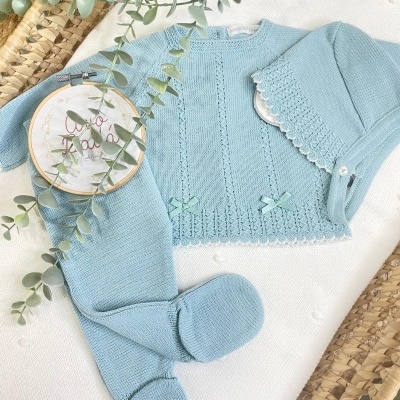 Conjunto de bebé em malha azul clara com casaco, calças e gorro decorativo