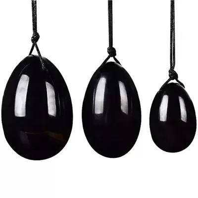 Três ovos negros brilhantes pendurados em cordões pretos