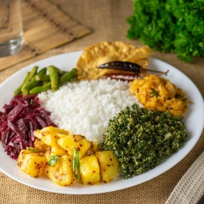 Prato com arroz, batatas, legumes variados e pimenta seca sobre mesa rústica