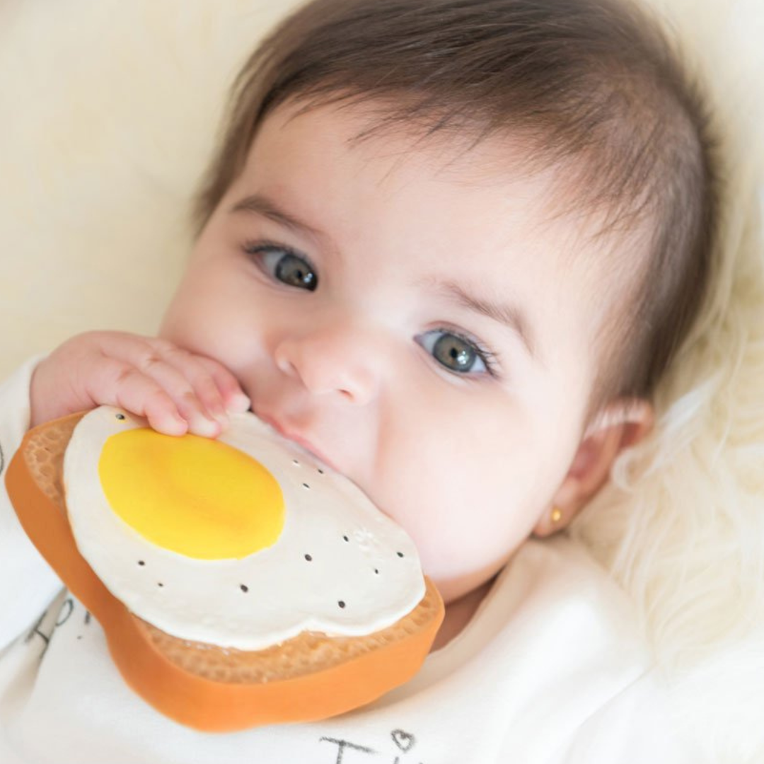 Bebé a morder brinquedo de borracha torrada com ovo estrelado