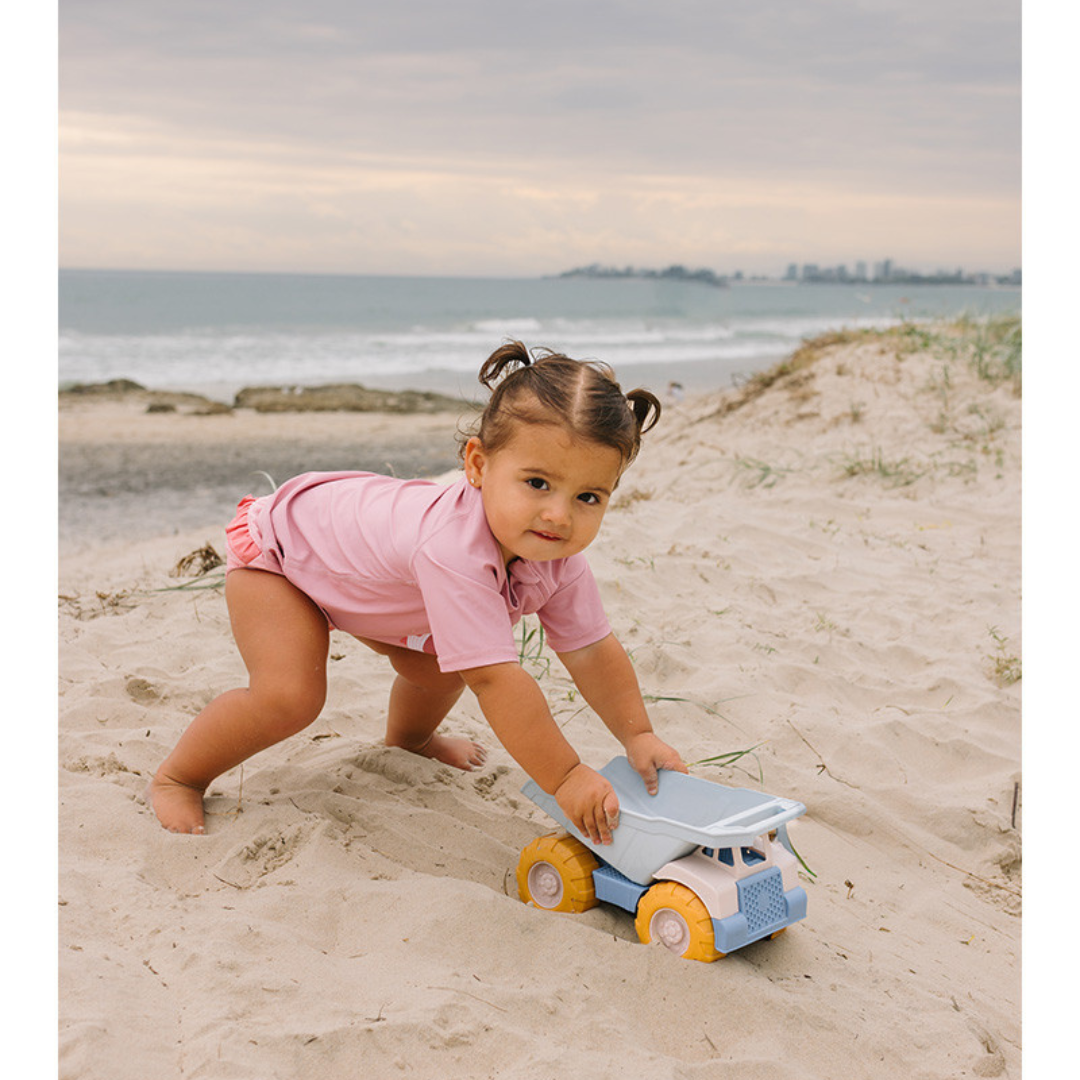 Criança a brincar com camião de brinquedo na praia