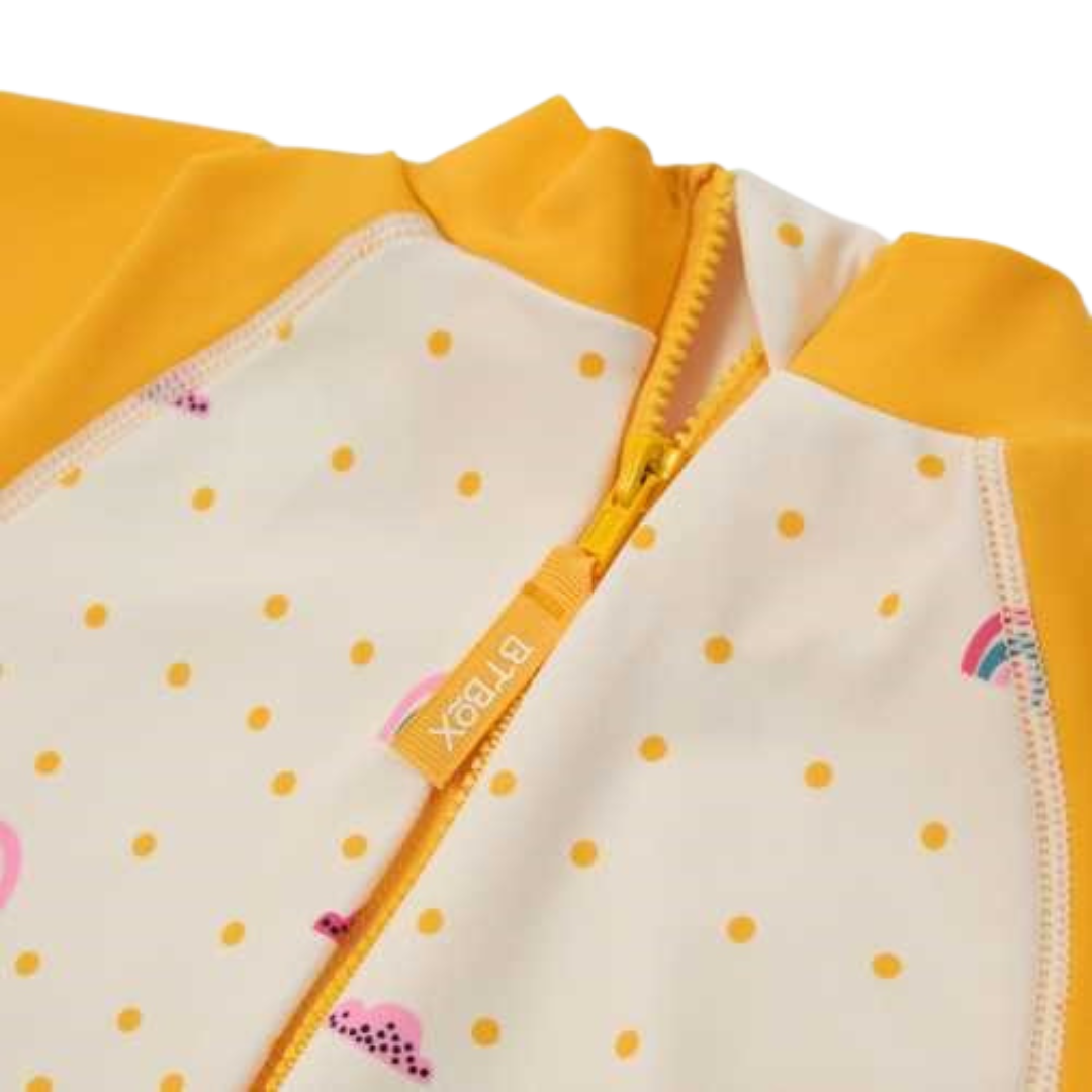 Roupa de criança branca com pontos amarelos e fecho amarelo