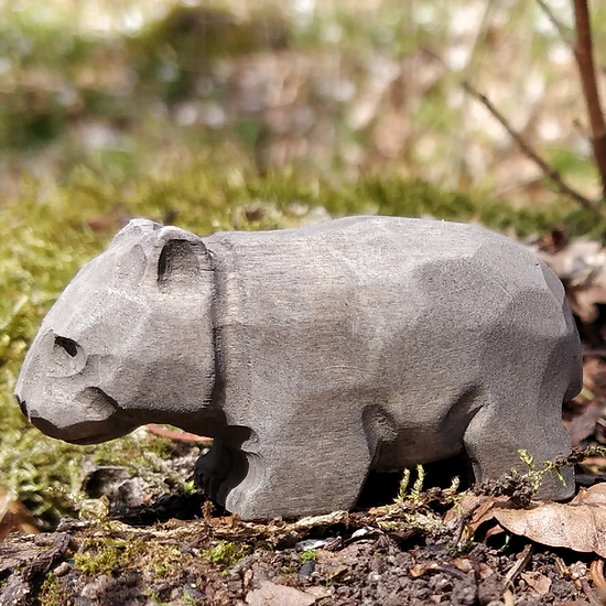 Estatueta de madeira cinzenta em forma de hipopótamo em ambiente natural