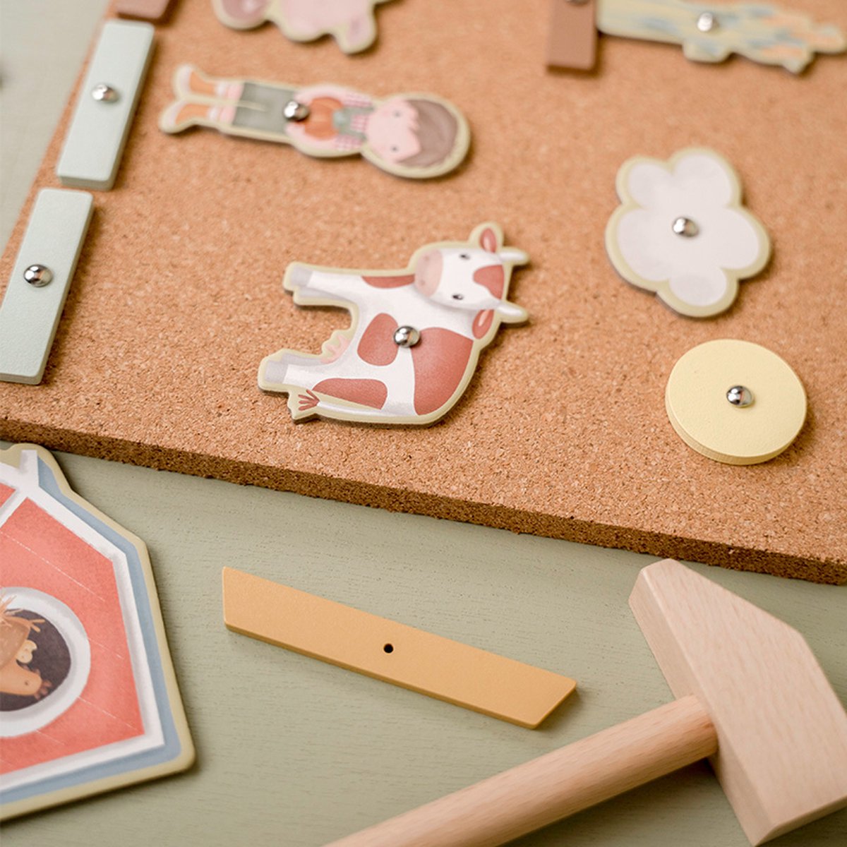 Peças de madeira coloridas em tabuleiro de cortiça com martelo de madeira