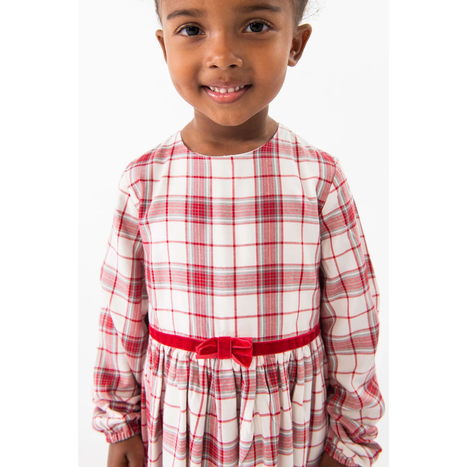 Vestido infantil branco com padrão aos quadrados vermelhos e cinto de veludo vermelho com laço.
