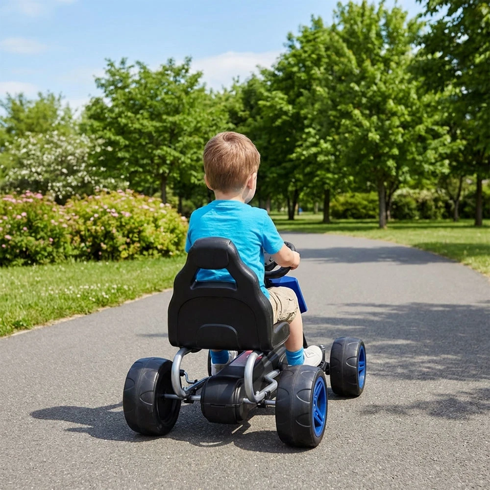 Criança em kart infantil em parque com árvores e relva