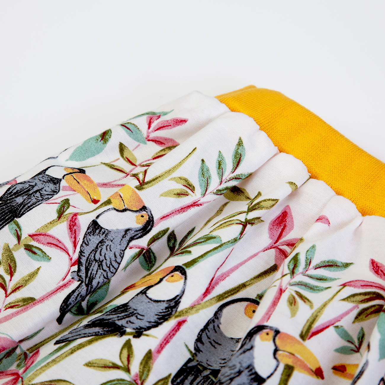 tecido com padrão de tucanos e folhas com cós amarelo elástico