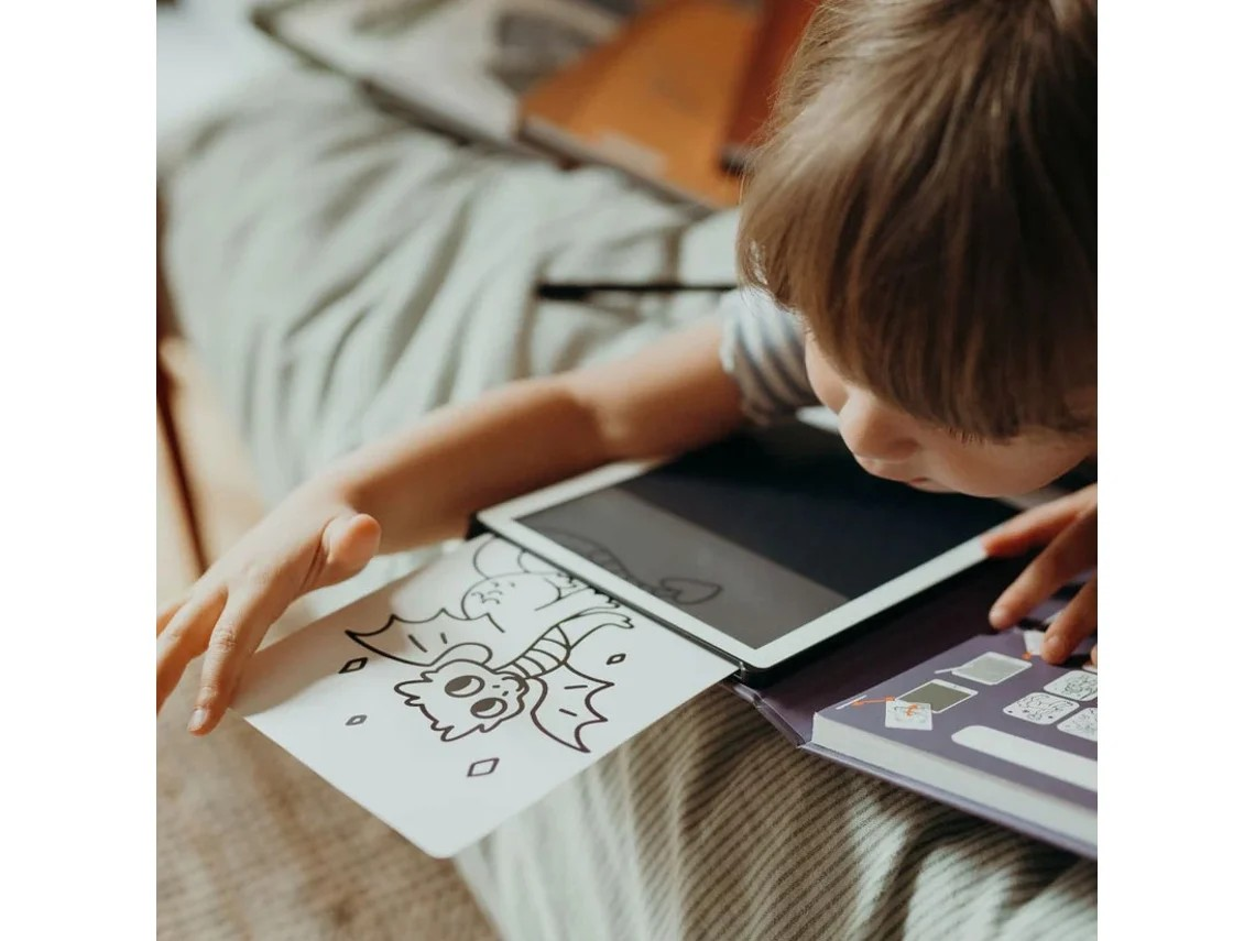 Criança deitada com tablet e desenho de monstro a preto e branco