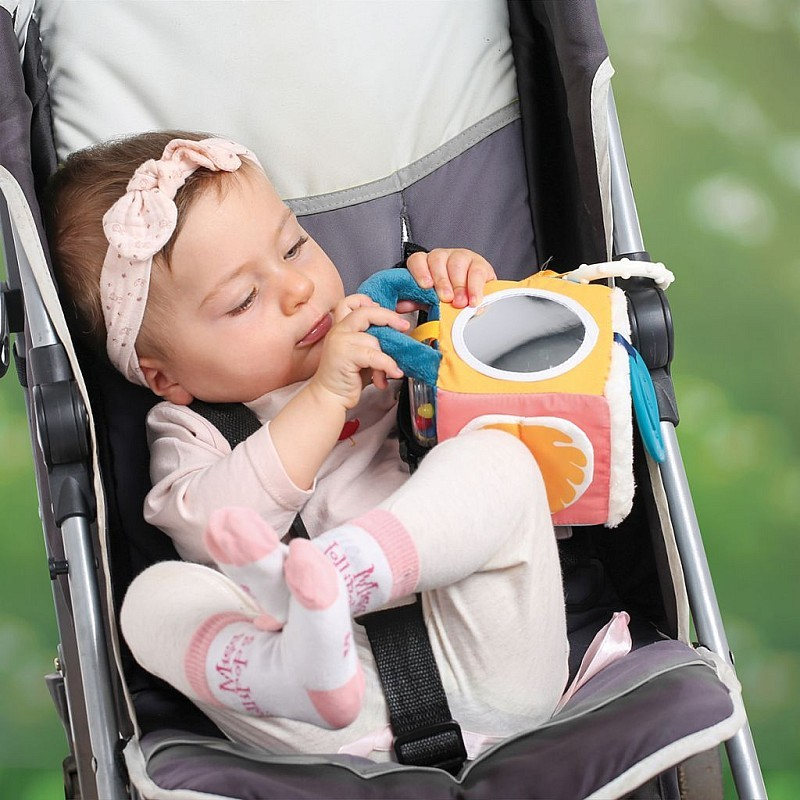 Criança num carrinho a brincar com brinquedo de tecido colorido com espelho