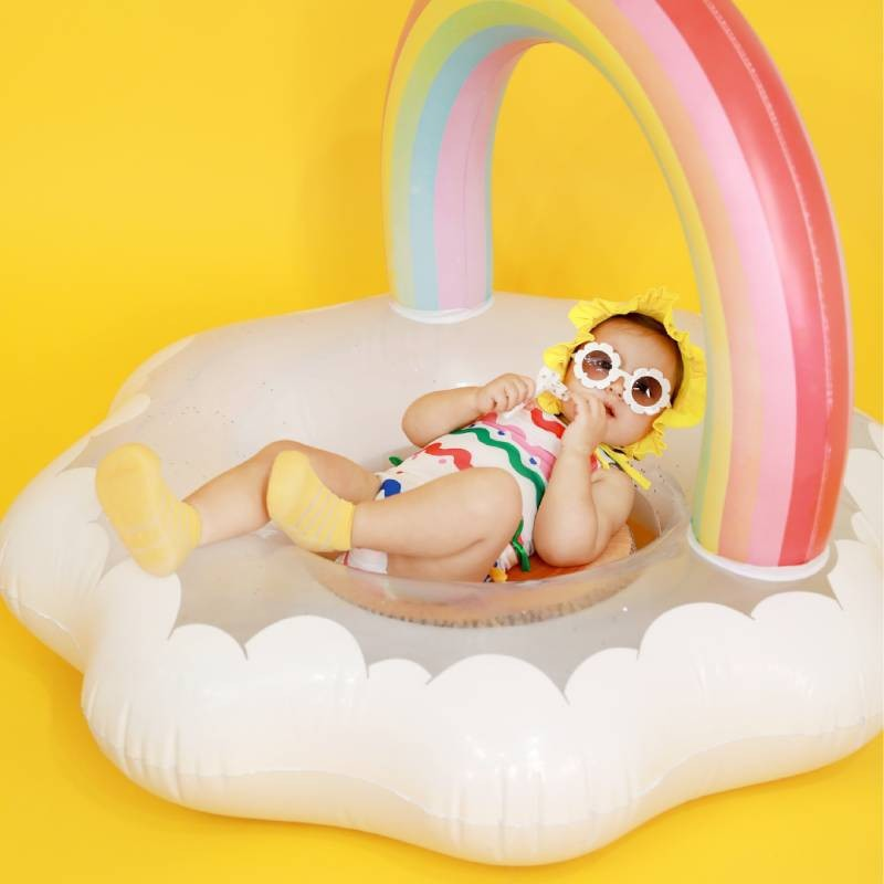 Criança numa piscina insuflável em forma de nuvem com arco-íris colorido
