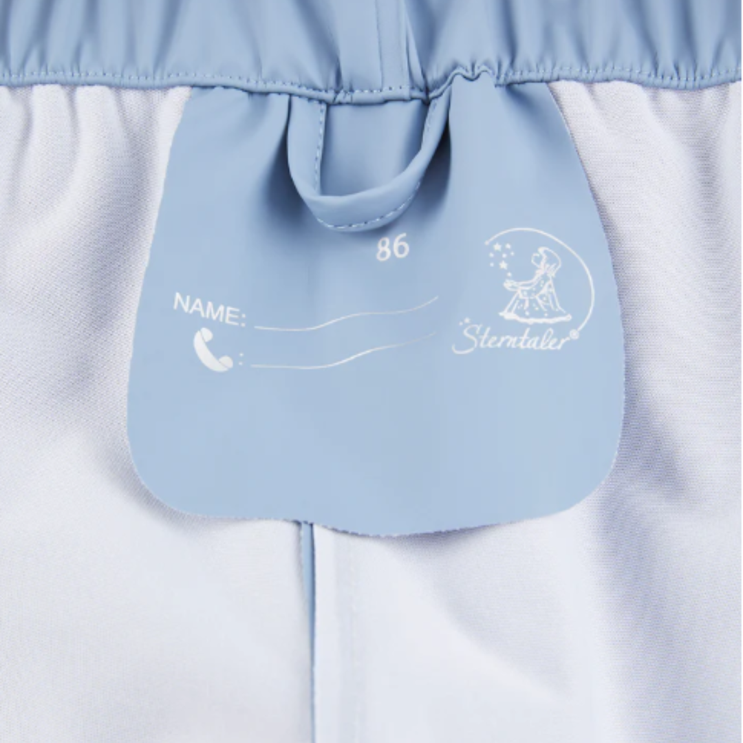 Etiqueta azul numa peça de roupa branca e azul claro com textos e logotipo Sterntaler