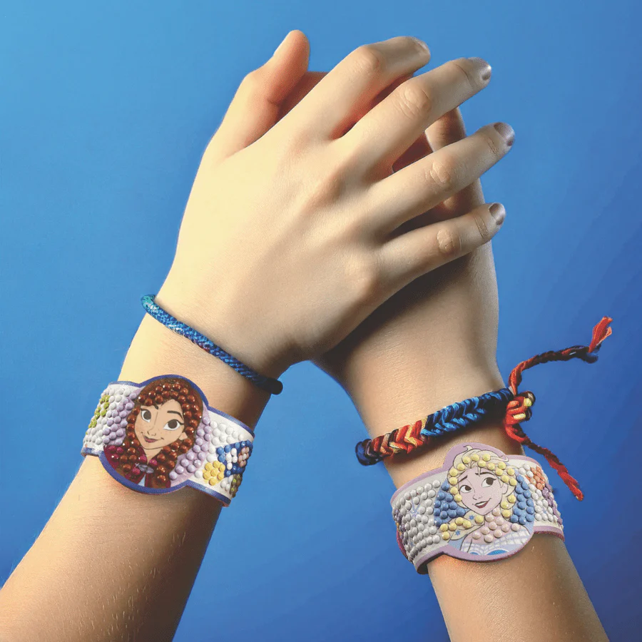 Dois pulsos com pulseiras artesanais de personagens animadas e fios trançados em fundo azul