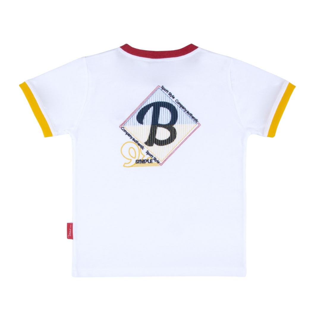 T-shirt branca infantil com gola vermelha e punhos amarelos nas mangas, estampada com losango colorido e texto nas costas.