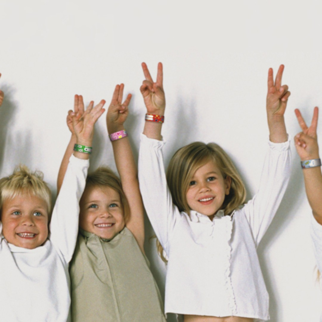 Crianças com pulseiras coloridas levantando as mãos