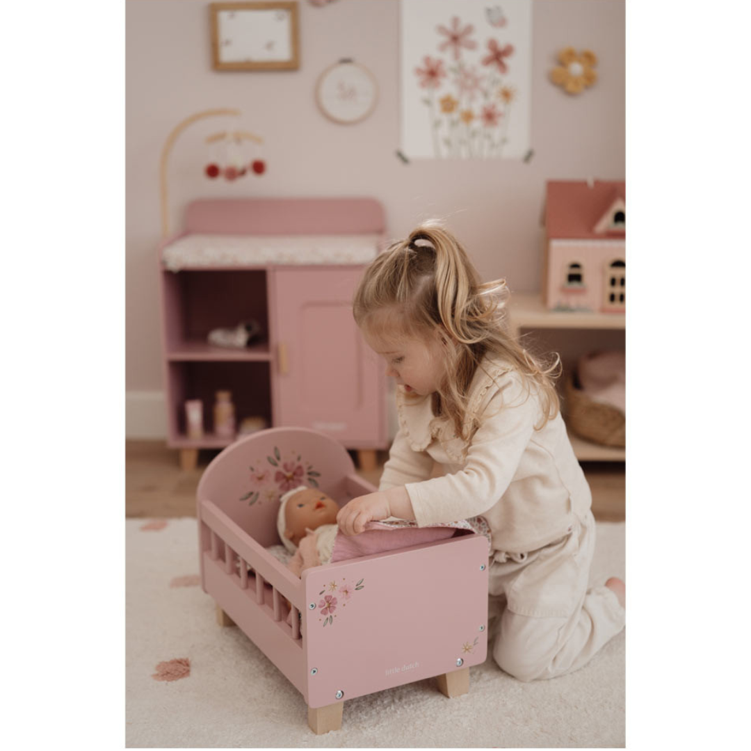 Cama para bonecas rosa com decoração floral e menina a brincar