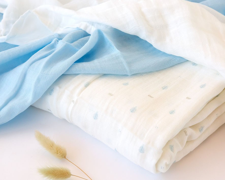 Tecidos brancos e azuis com padrão de gotas azuis e ramos secos claros