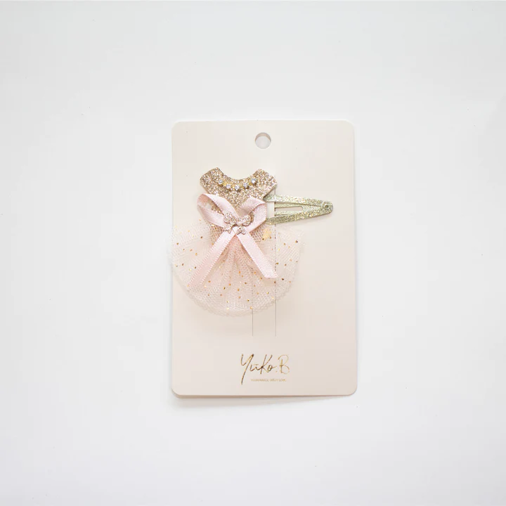 Presilha de cabelo infantil com vestido dourado, laço rosa e tule em cartão branco