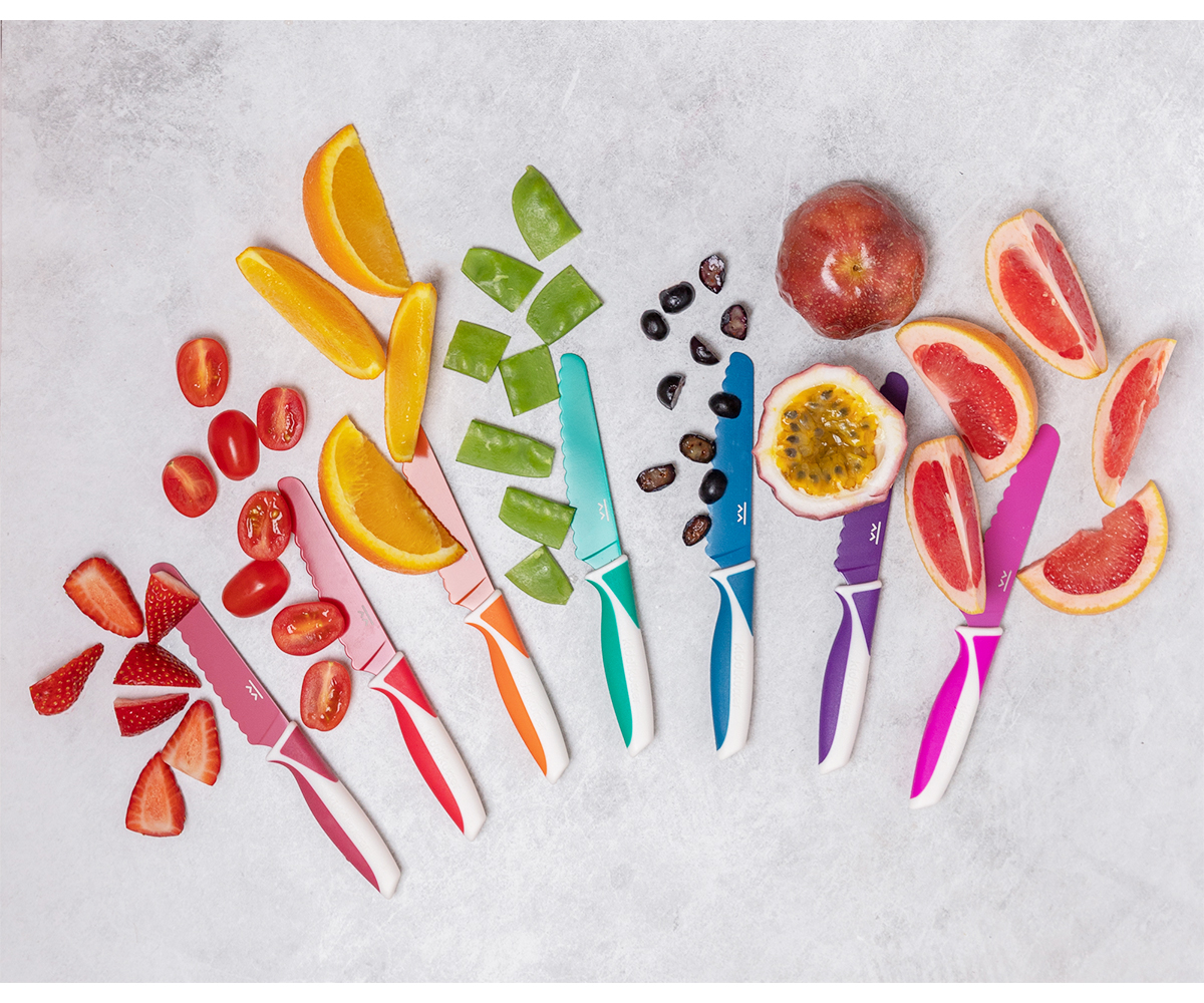 Seis facas coloridas com frutas cortadas sobre superfície cinza