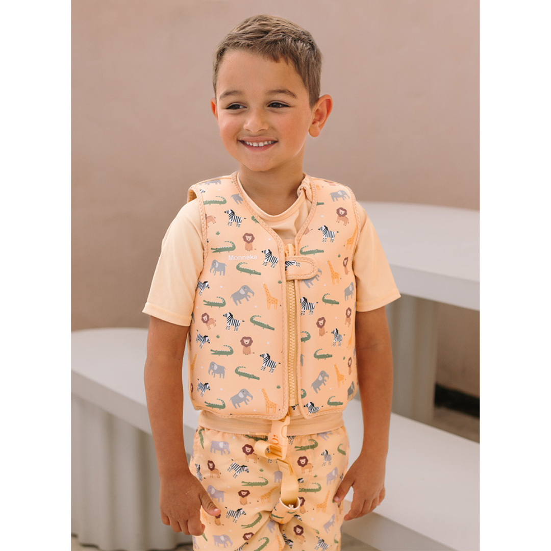 Criança com colete infantil pêssego com padrão de animais e roupa combinando.