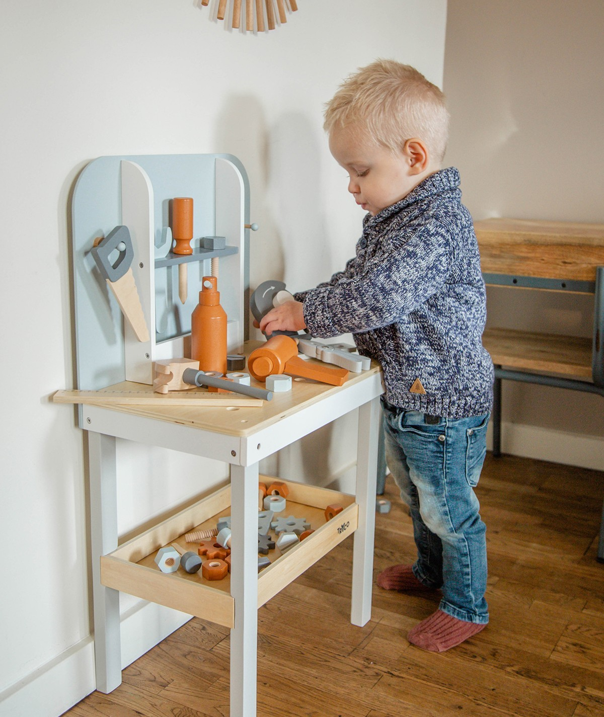 Criança a brincar com banca de ferramentas de madeira
