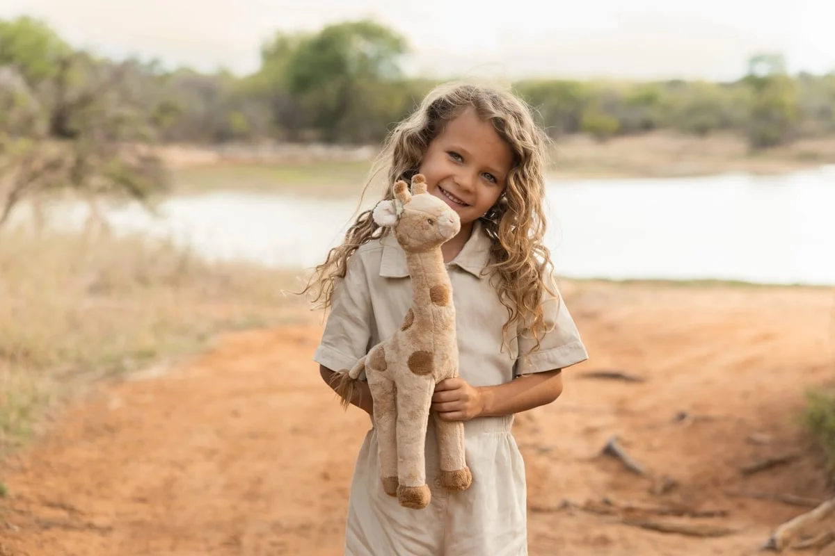 Menina segurando brinquedo de pelúcia girafa ao ar livre
