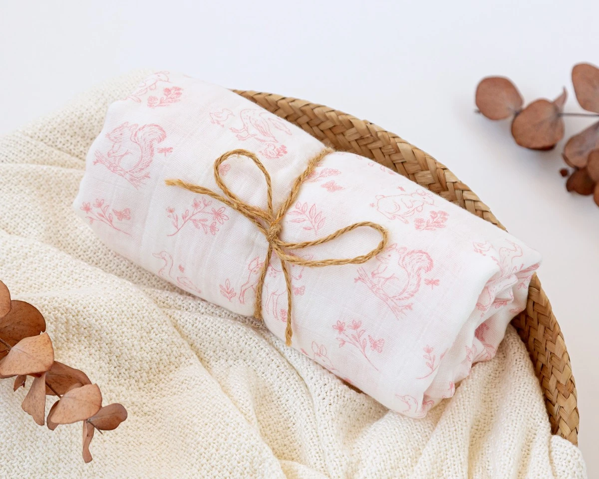 Tecido branco estampado enrolado numa cesta de vime com folhas secas ao lado