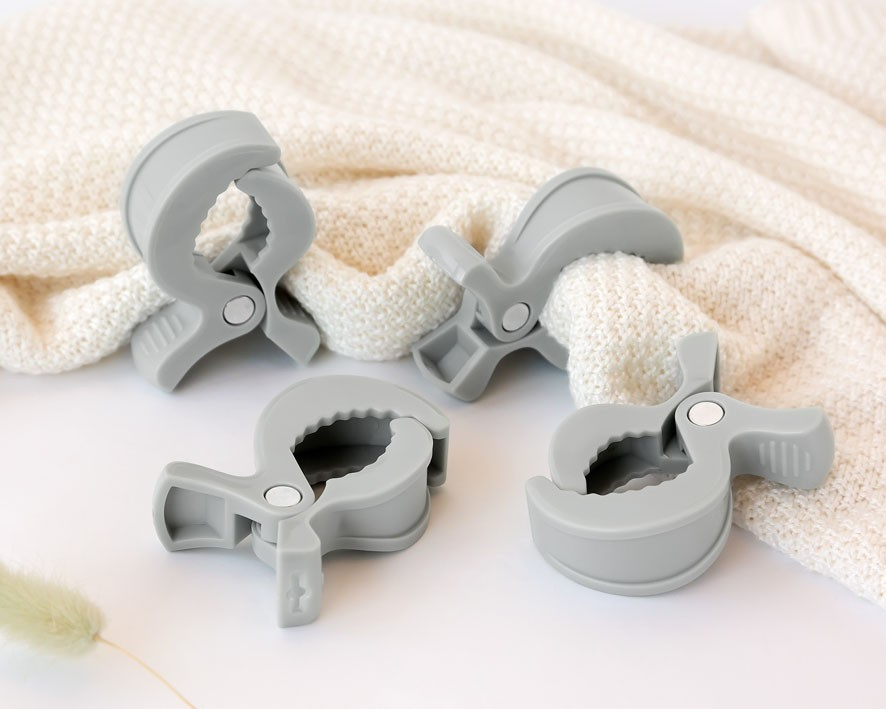 Quatro grampos de silicone cinza claro sobre tecido de malha bege