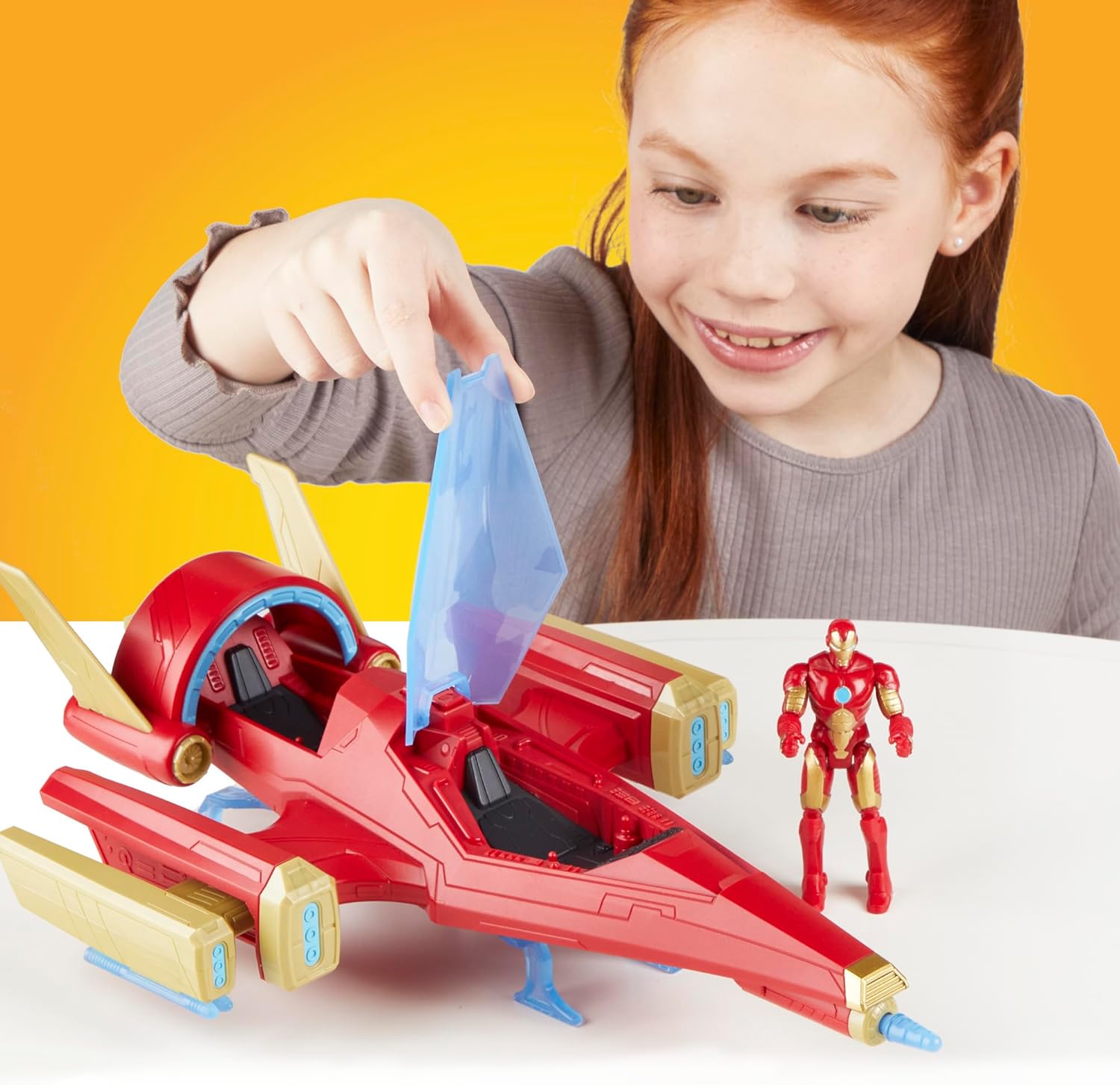 Menina ruiva a sorrir a brincar com brinquedo de nave espacial e figura do Homem de Ferro