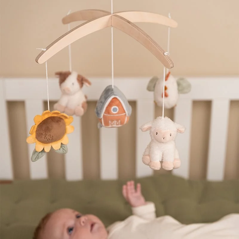 Mobile de berço com figuras de tecido penduradas e bebé deitado no berço