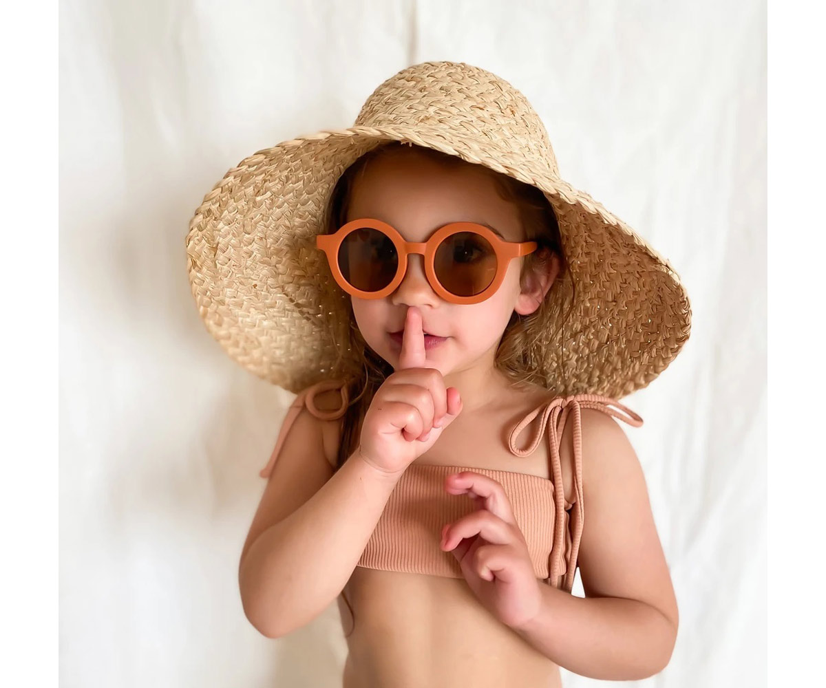 Criança com chapéu de palha largo e óculos de sol laranja