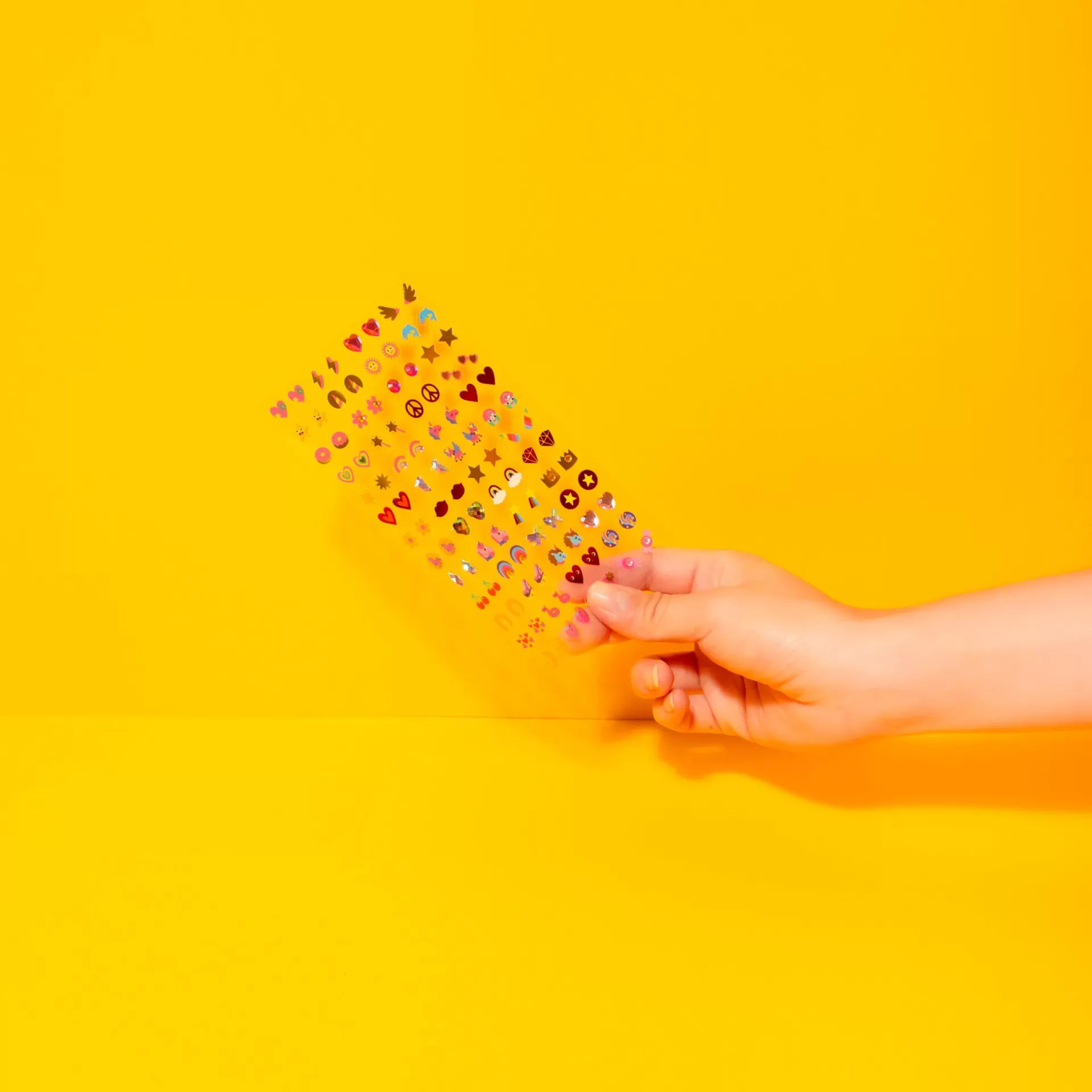 Mão segura cartão transparente com autocolantes coloridos sobre fundo amarelo