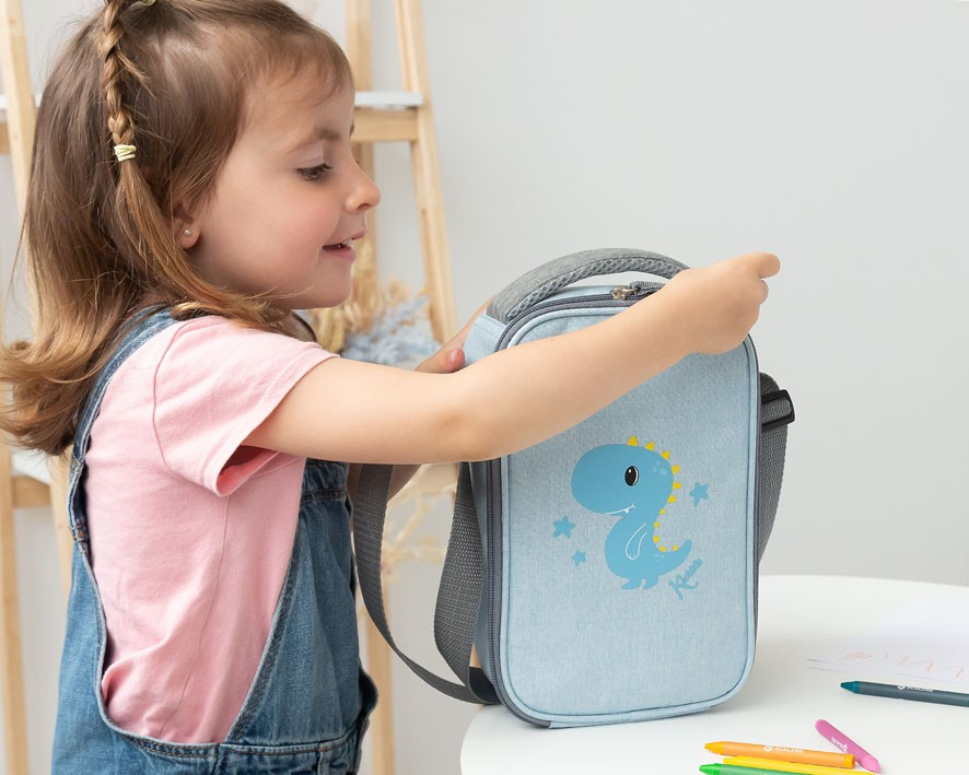 Mochila infantil cinzenta com padrão de dinossauro azul, segurada por uma menina.