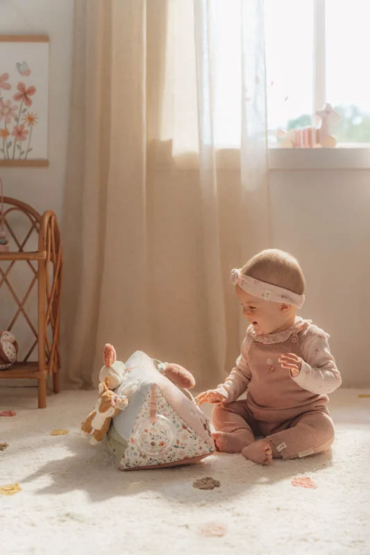 Bebé sentado a brincar com brinquedo têxtil em sala clara