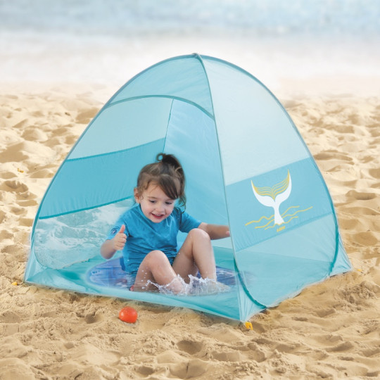 Tenda azul de praia com baleia na areia e criança dentro
