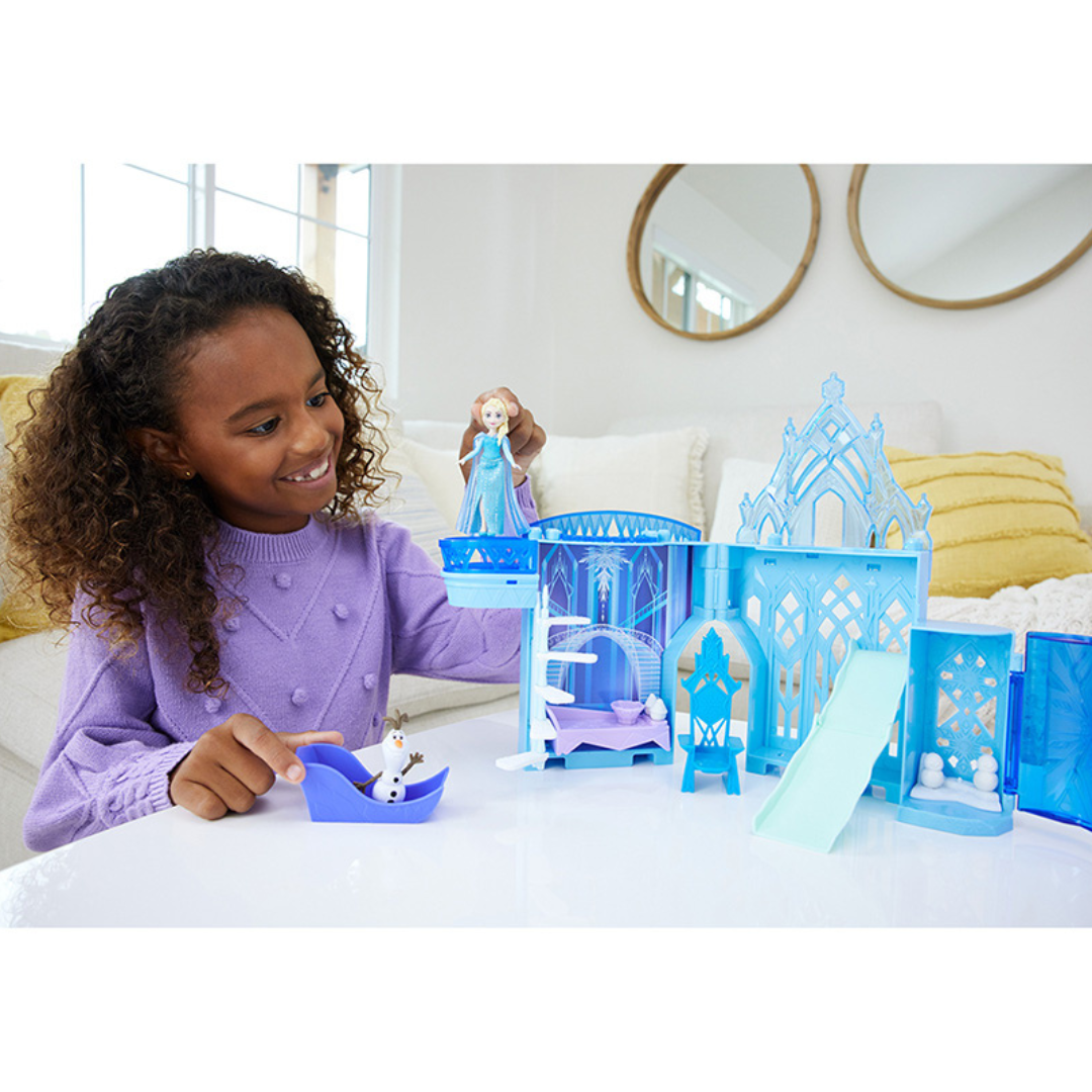 Menina a brincar com castelo de gelo e personagens de brinquedo numa mesa