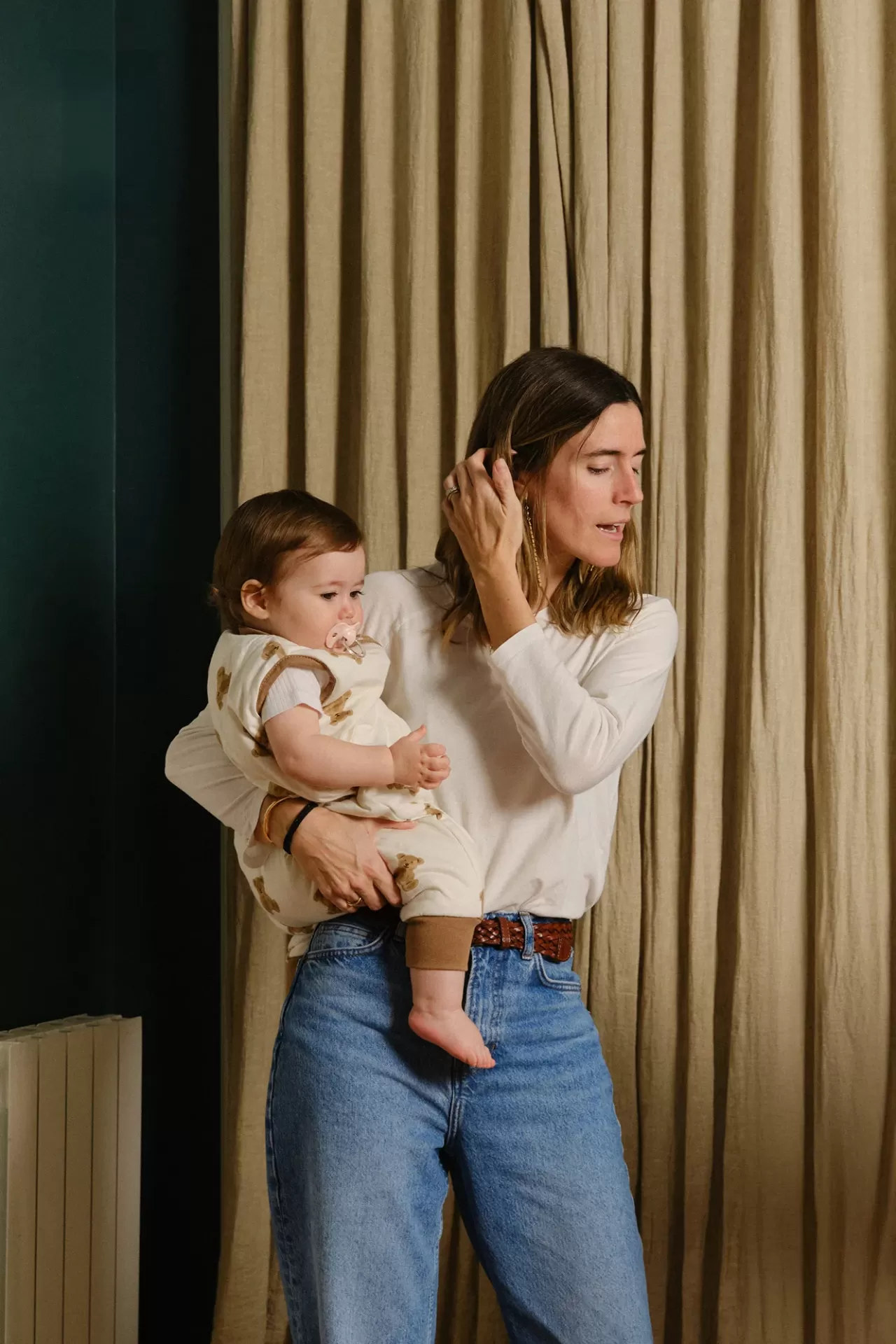 Mulher com bebé em interior com cortinas bege ao fundo