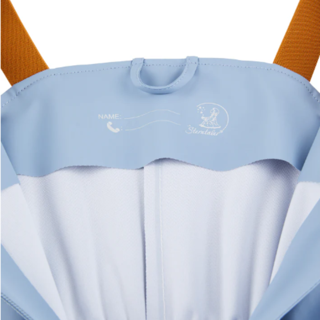 Interior de mochila azul claro com espaço para nome e telefone, alças laranja