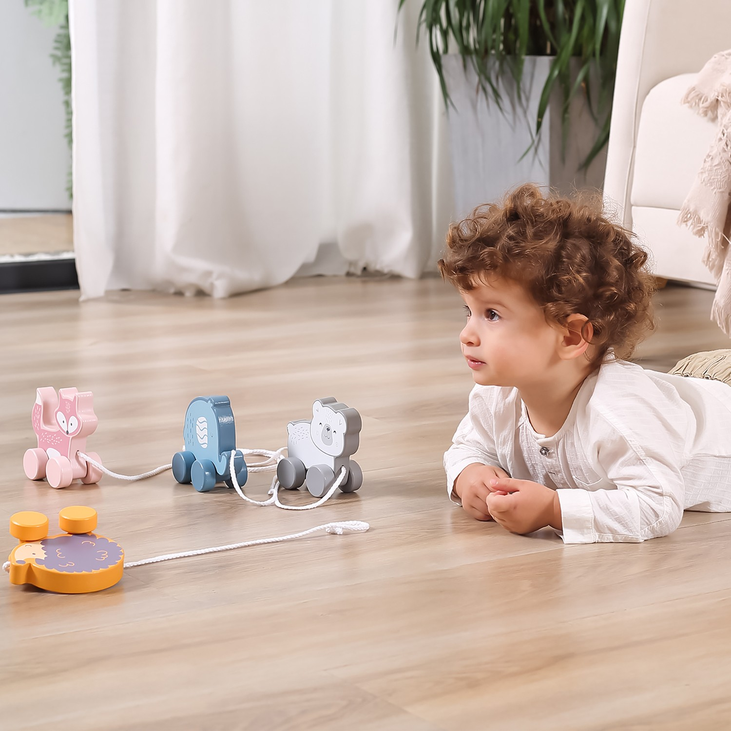 Brinquedo de puxar de madeira colorido com quatro peças no chão de madeira junto a uma criança.