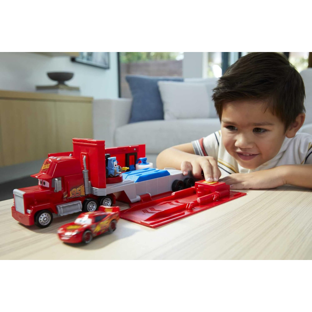 Brinquedo de camião vermelho com reboque e carro de corrida vermelho numa mesa com menino a brincar