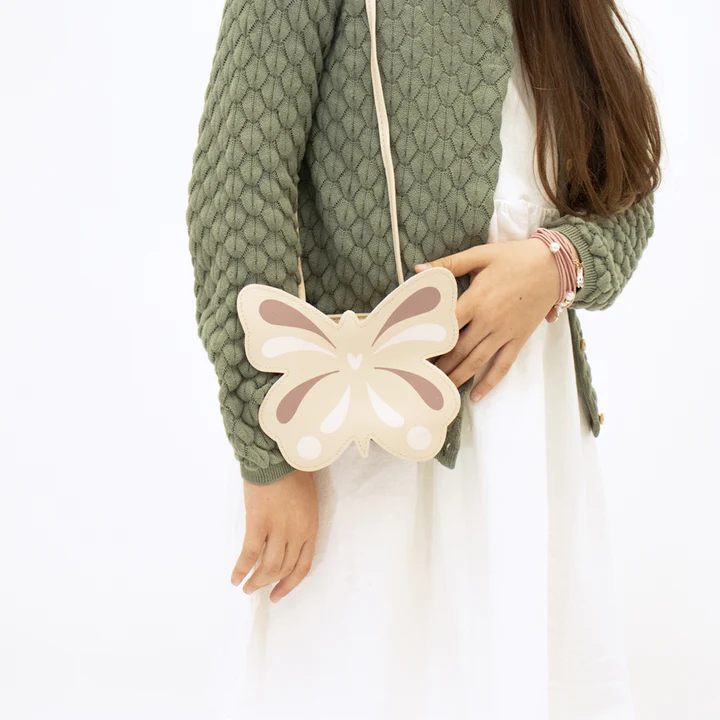 Mala borboleta bege e rosa claro usada com camisola verde e vestido branco